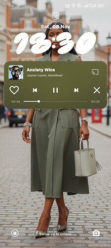 A person wearing a green midi dress and brown sandals is standing on a street, holding a white handbag, with buildings and a pedestrian crossing in the background. (Captioned by AI)