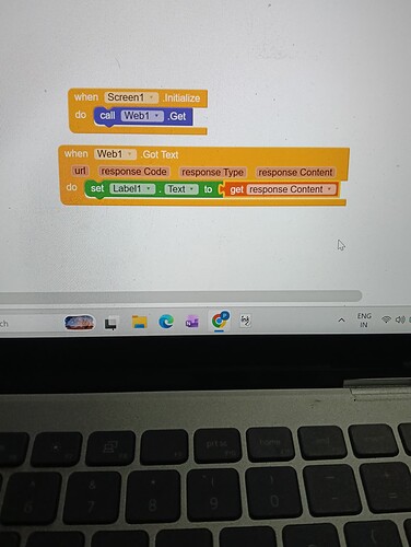 A computer screen displays a colorful block-based programming interface with blocks labeled 'set task_status to Timer1.Timer' and others related to restarting a timer and setting text fields, with part of a keyboard visible at the bottom. (Captioned by AI)