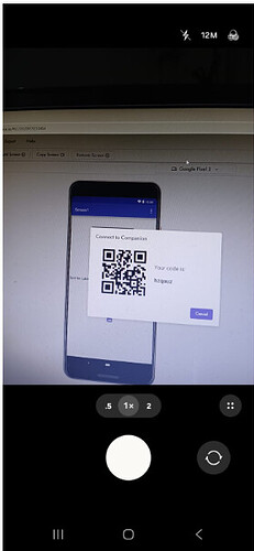 A smartphone camera screen captures a computer display showing a QR code and a connection code for the Google Final platform. (Captioned by AI)